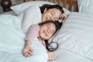 kindermatras met daarop moeder en kind die onder een dekbed liggen