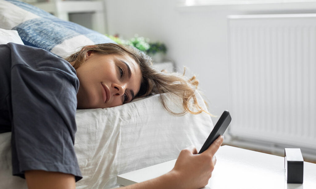 omkeerbaar matras met een vrouw erop die op haar telefoon zit